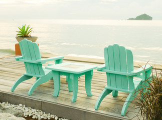 two blue chairs on a beach with beautiful view of the sea