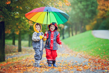 Sticker - Two adorable children, boy brothers, playing in park with umbrel