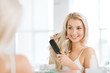 © Syda Productions - happy woman brushing hair with comb at bathroom