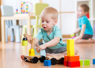 Wall Mural - Children boys playing with toy crane in playroom