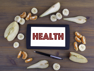 Wall Mural - Different fruits around tablet with text Health