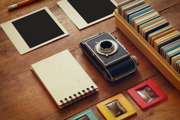 Canvas Print - top view of vintage camera and old slides frames over wooden table background
