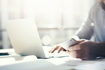 Businessman working with generic design notebook. Holding smartphone in hands. Horizontal, sunlight effects