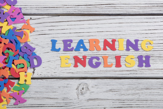 the colorful words learning english made with colorful letters over white wooden board