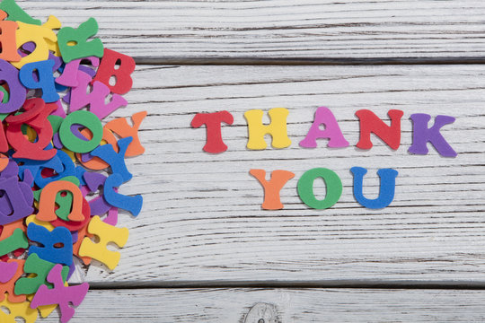 the colorful words thank you made with colorful letters over white wooden board