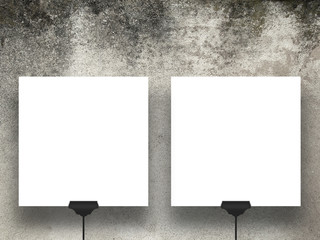 Close-up of two hanged square paper sheets with black clips on weathered concrete wall background