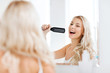 © Syda Productions - happy woman singing to hair brush at bathroom