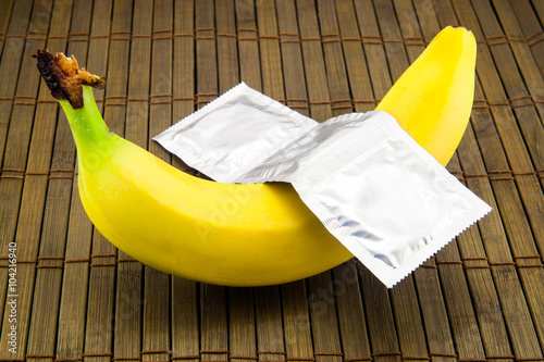 Fotografia, Obraz Banana with condom on wooden background