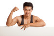 © halfbottle - Muscular Asian man flexing biceps behind  blank sign