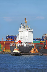 Tugboat assisting container cargo ship