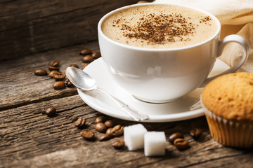 Close-up of coffee cup with roasted coffee beans on wooden backg