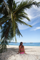 Wall Mural - young girl resting on the beach under a palm tree