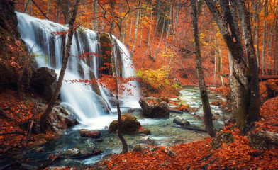 Wall Mural - beautiful waterfall at mountain river in colorful autumn forest with red and orange leaves at sunset