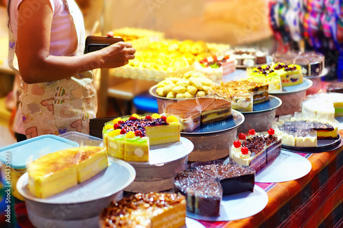 Fotografía sweet tasty cakes on display at pastry stall, at night street market