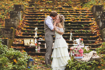 Wedding couple in a rustic style kissing near the stone steps surrounded by wedding decor