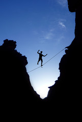 Wall Mural - Man walking on tight rope over the rock