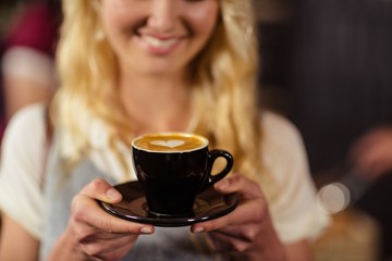  Portrait of smiling pretty customer holding cup of coffee 