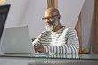 © Westend61 - Portrait of smiling man sitting at his desk working with laptop