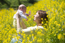 Mother With Her Baby Girl On Yellow Blossoming Field Of Flowers