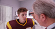© rocketclips - Mid-aged doctor examining football player after concussion
