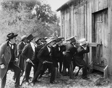 Group Of Men With Guns And Top Hats Breaking Into A Barn 