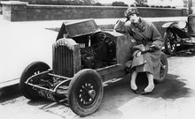 Young Woman Sitting Next To Small Car Looking At The Engine In Disbelieve 