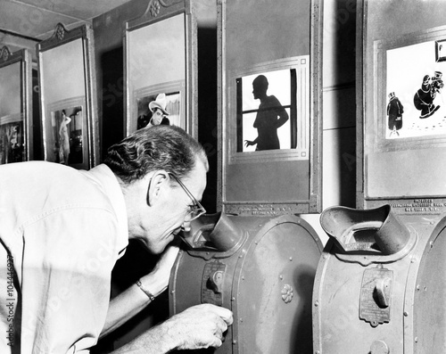 Fotografía Man looking into a nickelodeon film machine