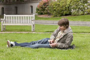 College student listening to digital music audio device on university campus