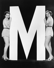 Wall Mural - Two women posing with huge letter M 