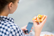 © Martinan - Teenager eating pizza looking in phone
