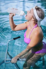 Poster - Fit woman doing underwater bike and drinking water
