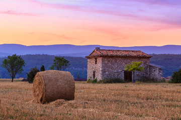 Wall Mural - Sunset over farm field with hay bales near Sault