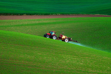 Farm machinery spraying insecticide to the green field, agricultural natural seasonal spring background