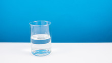 Half Empty Or Half Full Glass Of Water On White Table. (For Positive Thinking When See The Glass Is Half Full.)