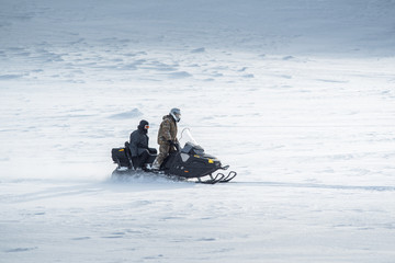 two men on a snowmobile ride fast