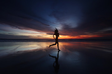 Wall Mural - Woman running on the beach at sunset