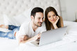 © BGStock72 - Young couple with laptop in the bed