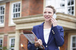 © highwaystarz - Female Realtor On Phone Outside Residential Property