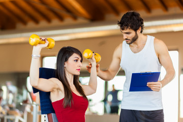 Personal trainer helping woman working with dumbbells