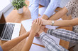 © rogerphoto - Business people joining hands over table. Start up team