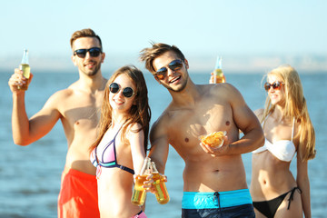 Wall Mural - Happy young friends drinking beer at the beach, outdoors