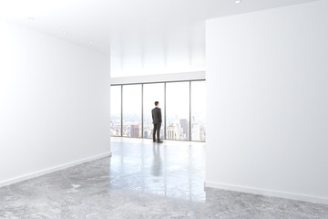 Poster - businessman looking out the window in empty office with concrete