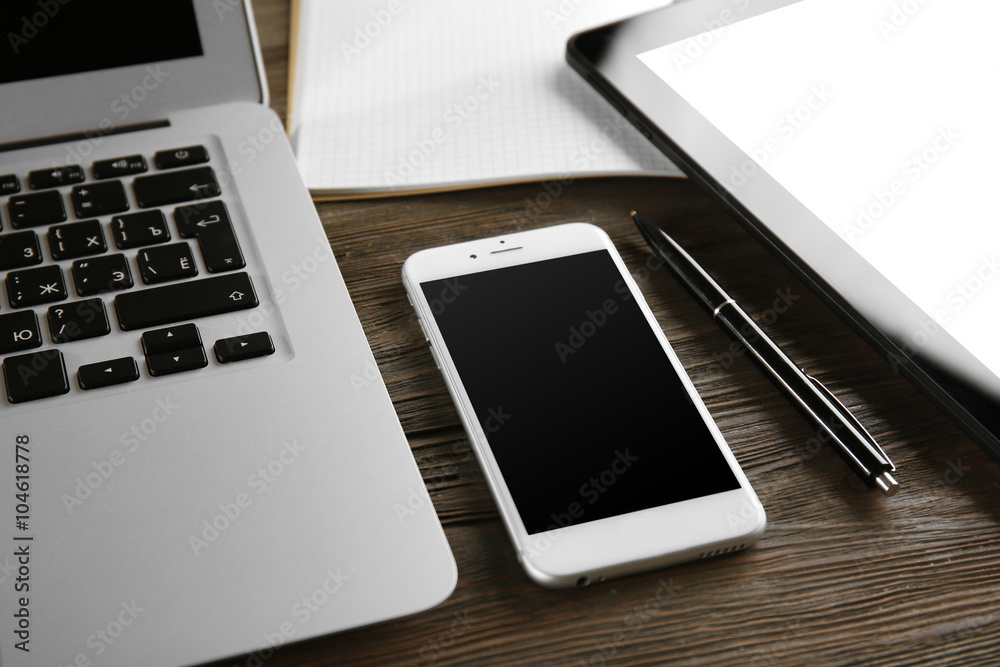 Modern laptop, tablet, mobile phone and notebook on the table, close-up