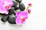 Fototapeta Storczyk - Beautiful composition of orchid and pebbles on white wooden background, copy space