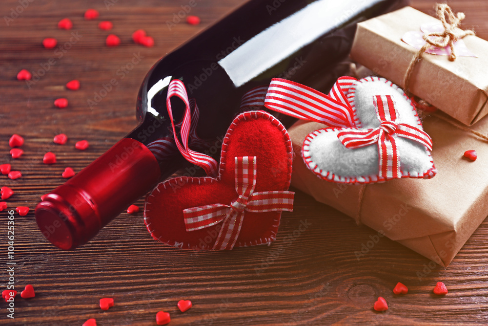 Red wine bottle and gift box on wooden background