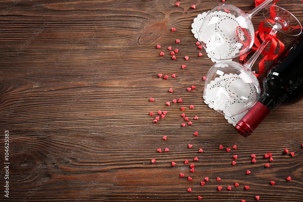 Wine bottle and glasses with handmade hearts on wooden background