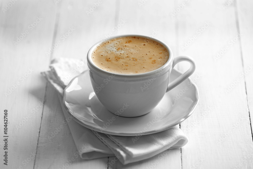 Cup of coffee with foam on wooden background