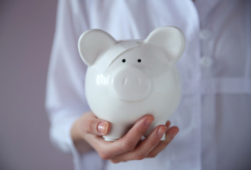 Canvas Print - Woman holding in hand white piggy bank with patch