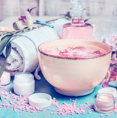 Wall Mural - Wellness setting with orchid flowers floating in bowl of water with spa and cosmetic tools . Vertical composing. Pastel toned