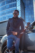 © Fxquadro - Serios blackman in sunglasses standing near the car with modern building on background